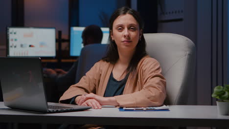 retrato de una mujer de negocios sonriente mirando a la cámara mientras está sentada en un escritorio