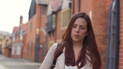 woman outdoors walking to work along city street lined with houses 1