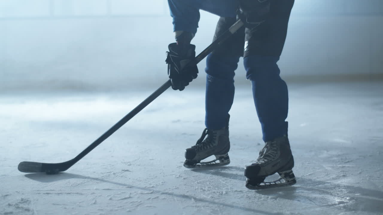 retrato de un jugador de hockey masculino concentrado sosteniendo un palo y mirando la cámara en la arena de hielo