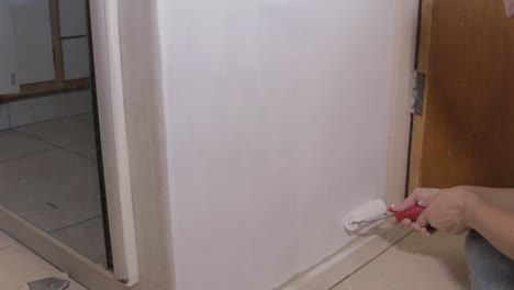 bloqueado gran angular de pintura de imprimación de mujer en un armario con un rodillo