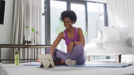 happy african american wearing sportswear, exercising, using tablet