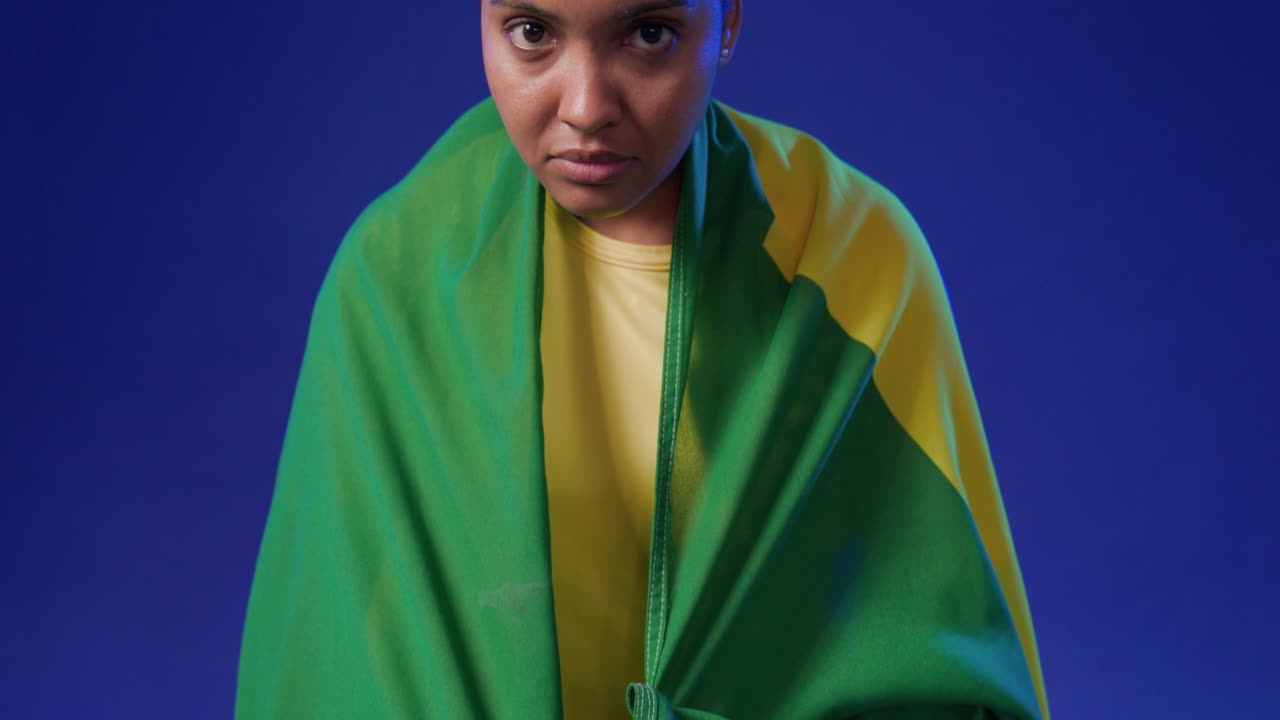 Donna africana palleggia un pallone da calcio sull'erba sintetica in divisa gialla, drappeggia una bandiera verde-gialla, mostrando orgoglio.