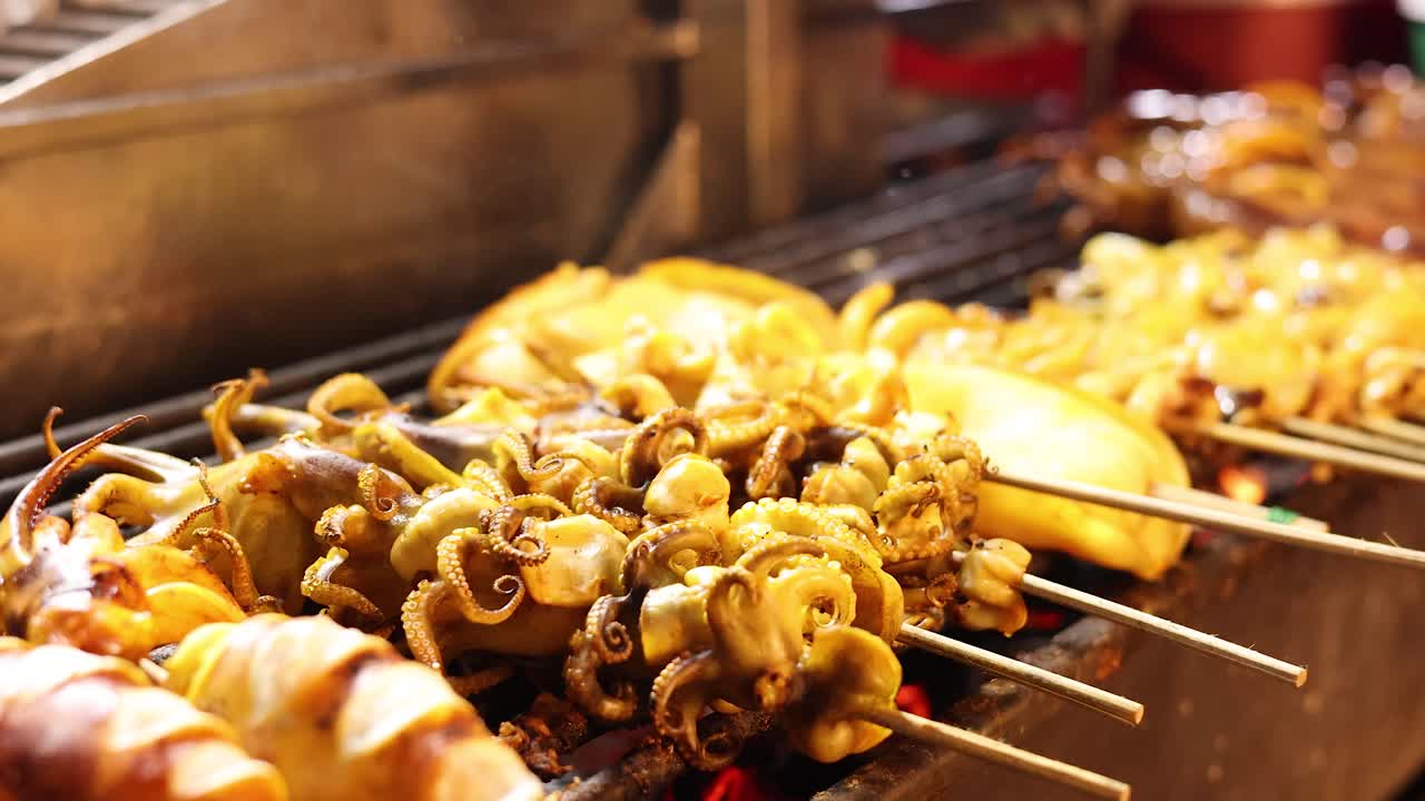 Close-up of squid skewers grilling over open flame, vibrant lighting, shallow depth of field