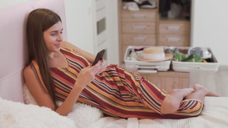hermosa chica elige viajar por teléfono a dónde ir de vacaciones, la maleta se recoge en el fondo
