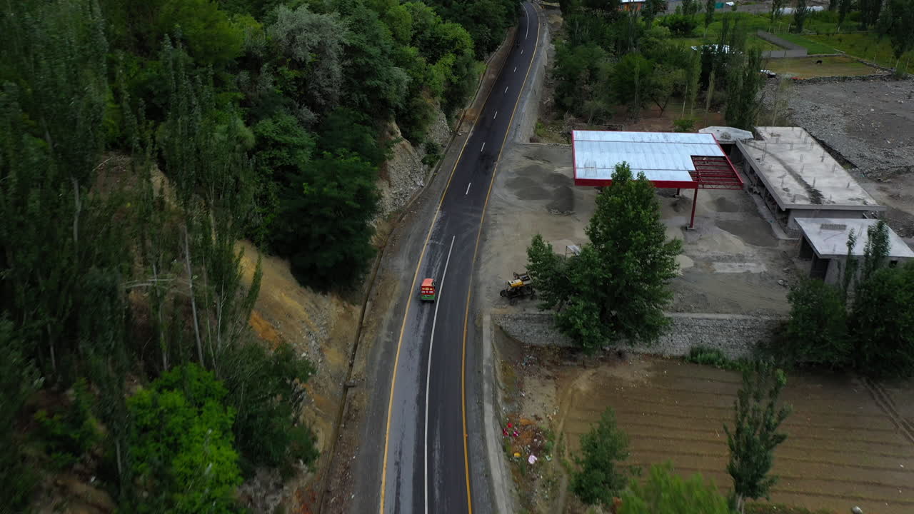 disparo dramático de un dron después de un tuk-tuk en la autopista karakoram pakistan en un pequeño pueblo o aldea, persiguiendo un tiro aéreo