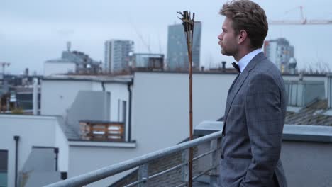 a nice suited man looking on his pocketwatch while the wind is blowing in his hair