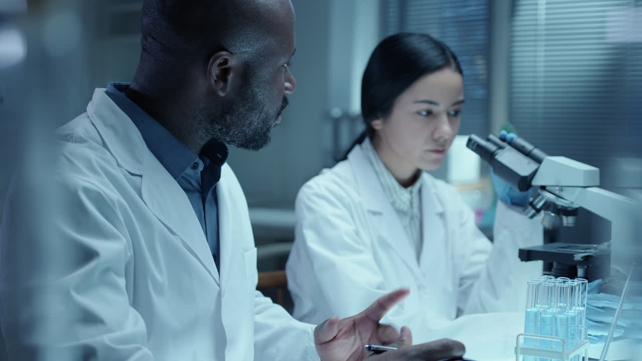 Female Scientist Conducting Lab Research with Assistance of Male Colleague