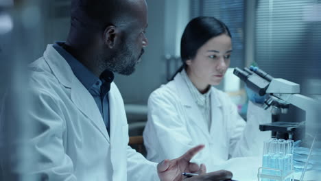 female scientist conducting lab research with assistance of male colleague