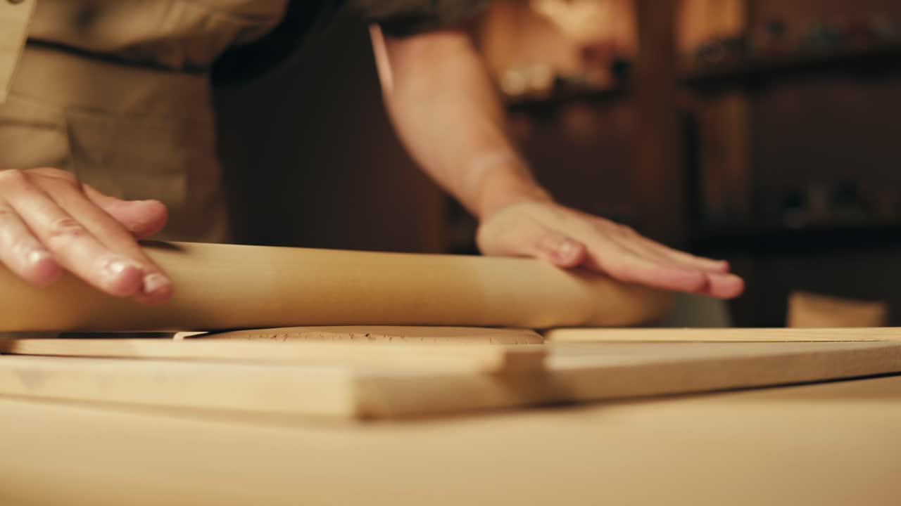 persona que enrolla arcilla con un rodillo