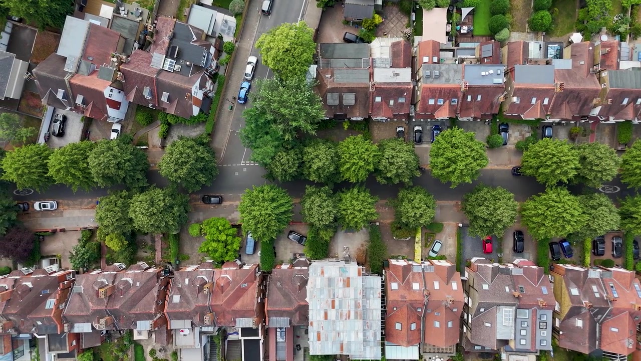 Vista dall'alto di una strada residenziale di Londra ovest fiancheggiata da alberi maturi e auto parcheggiate tra file di tetti in tegole