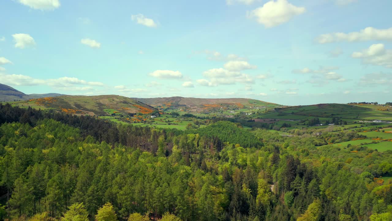 Diagonally travelling aerial video of the Mourne Mountains and Slieve Donard in Newcastle, County Down in Northern Ireland, UK on a bright and sunny day. Filmed in 4K, 60fps and with Rec709 Color.