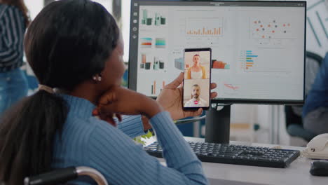 Back-view-of-african-woman-in-wheelchair-discussing-with-friends-on-video-call