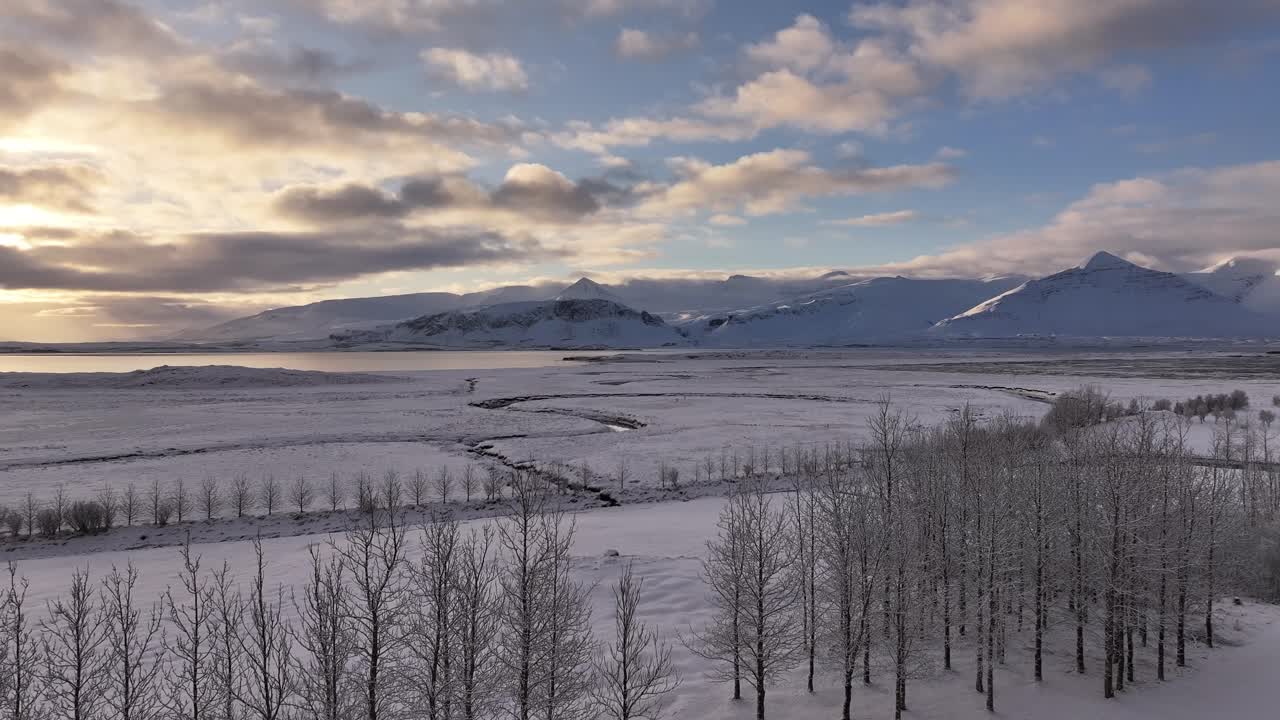 Borgarfjörður and Hafnarfjall mountains at sunrise, aerial drone view, snow-covered landscape, icy trees and calm sky