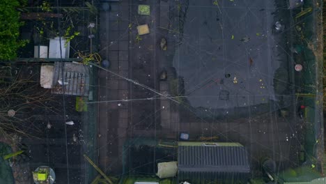 aerial descending shot over a bird sanctuary, revealing pools and visible birds under a net roof.