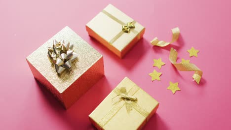 video of wrapped gold presents and stars on pink background