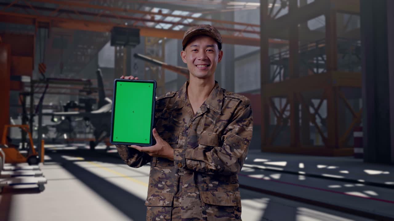 Soldado sorrindo vestindo uniforme camuflado segurando tablet com tela verde