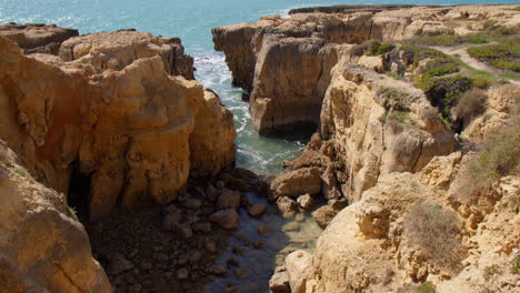 Landschaft-Aus-Orangefarbenen-Tonklippen-Am-Zerklüfteten-Ufer-Von-Praia-Do-Evaristo-In-Albufeira,-Algarve,-Portugal