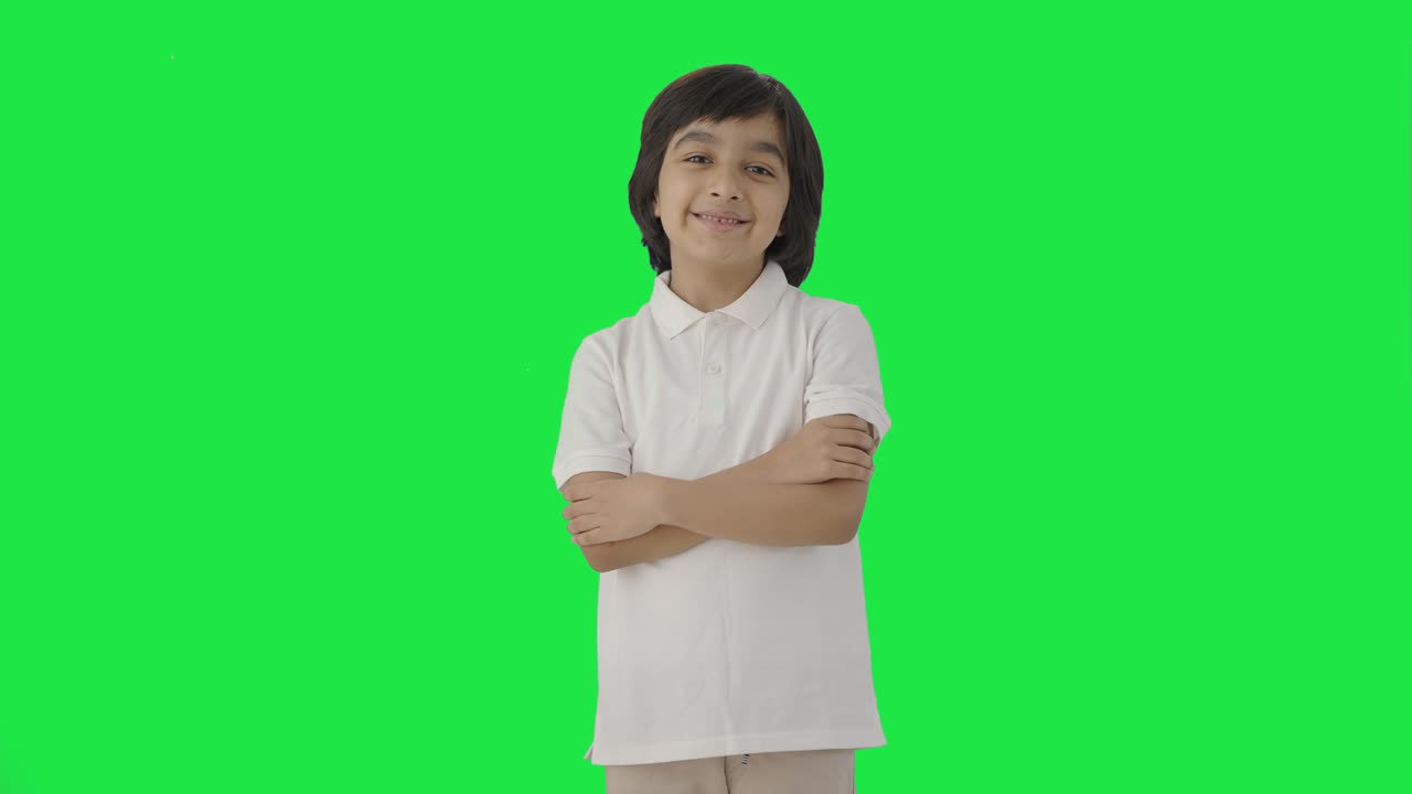 niño indio feliz de pie con las manos cruzadas pantalla verde