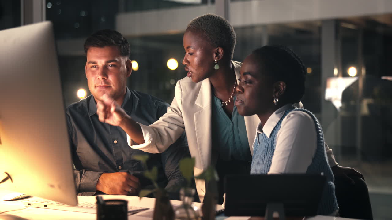 Three Business People Collaborating on Computer in Modern Office at Night