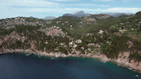 breathtaking view of port de soller village on rocky mountains near deià in mallorca, spain