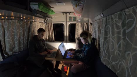 Two-people-in-a-camper-van-are-working-with-computers-and-phones,-time-lapse