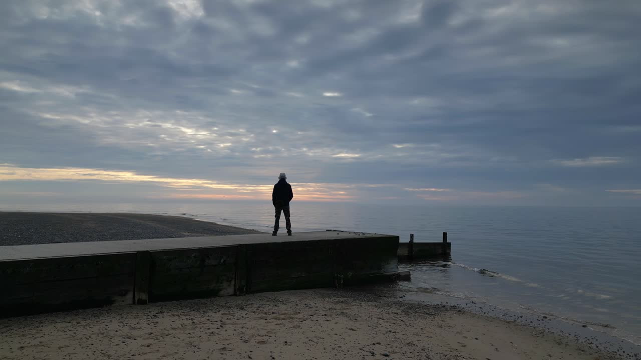 hombre de pie en el muelle al atardecer con la revelación de la costa de fleetwood beach lancashire reino unido