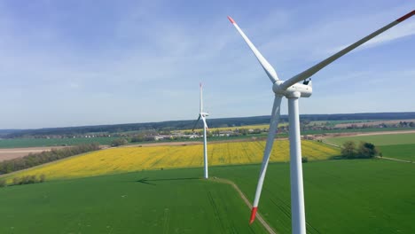 large wind turbines with blades in field aerial view, blue sky wind park slow motion drone turn