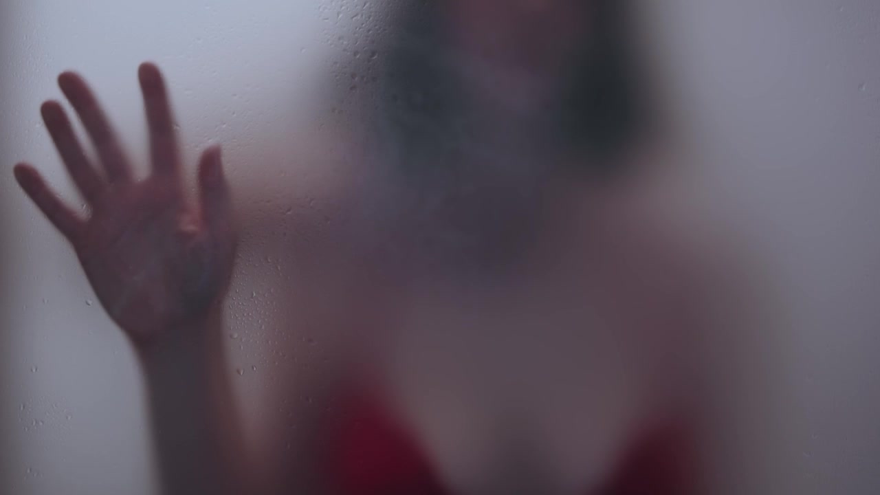 Donna attraente e bella che indossa lingerie rossa in un bagno appannato con un uomo dietro.