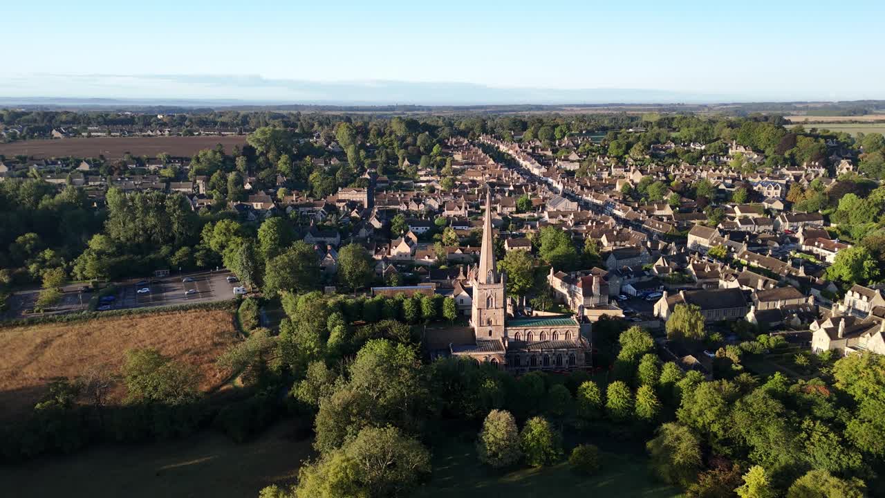 aerial drone flyover of the village of Burford in the Cotswolds, the historic church bathed in the early morning sunlight
