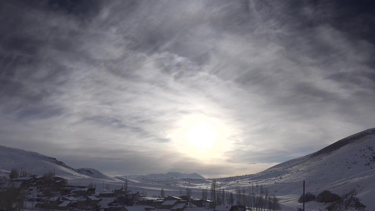 Paysage d'un village de montagne enneigé sous le soleil.