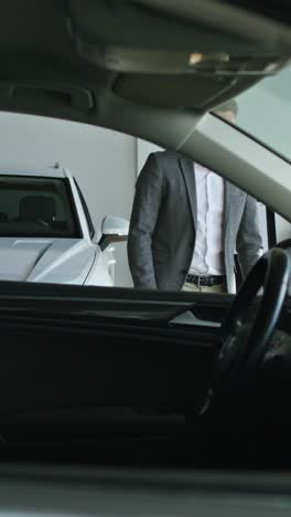 hombre de traje mirando un coche en un concesionario