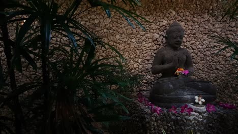 una vista panorámica de una hermosa estatua balinesa decorada colocada entre una pared característica y follaje verde