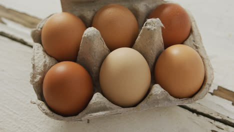video de vista aérea de huevos marrones en cartón de huevos en un fondo rústico