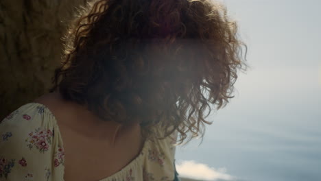 laughing girl shaking head sitting beach in front ocean close up. curls bouncing