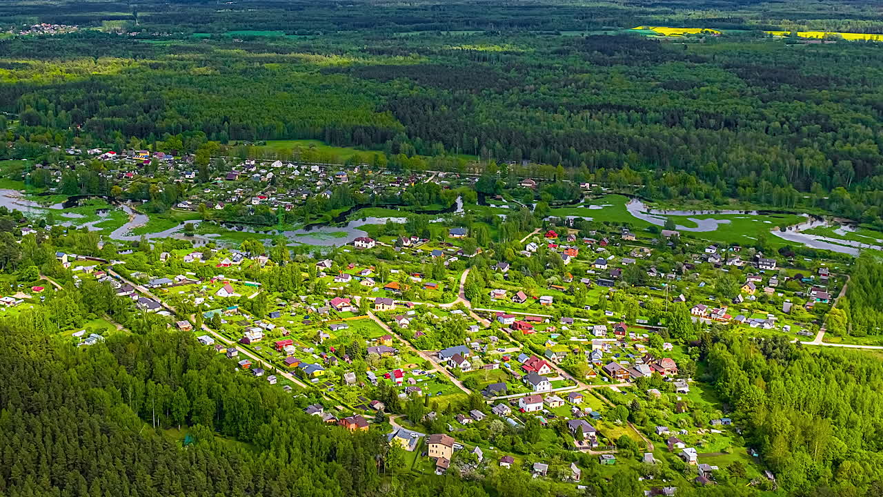 A village in the forest near Jelgava, Latvia from a high altitude aerial time lapse as cloud shadows pass over the picturesque suburb