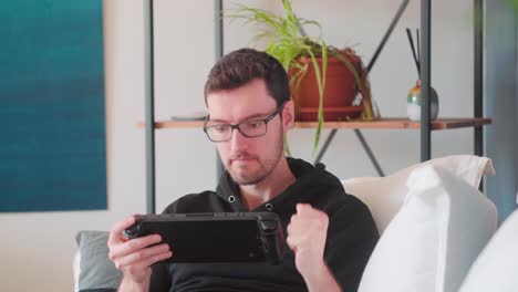 Junger-Hipster-Mann,-Der-Videospiele-Auf-Der-Handheld-Konsole-Spielt