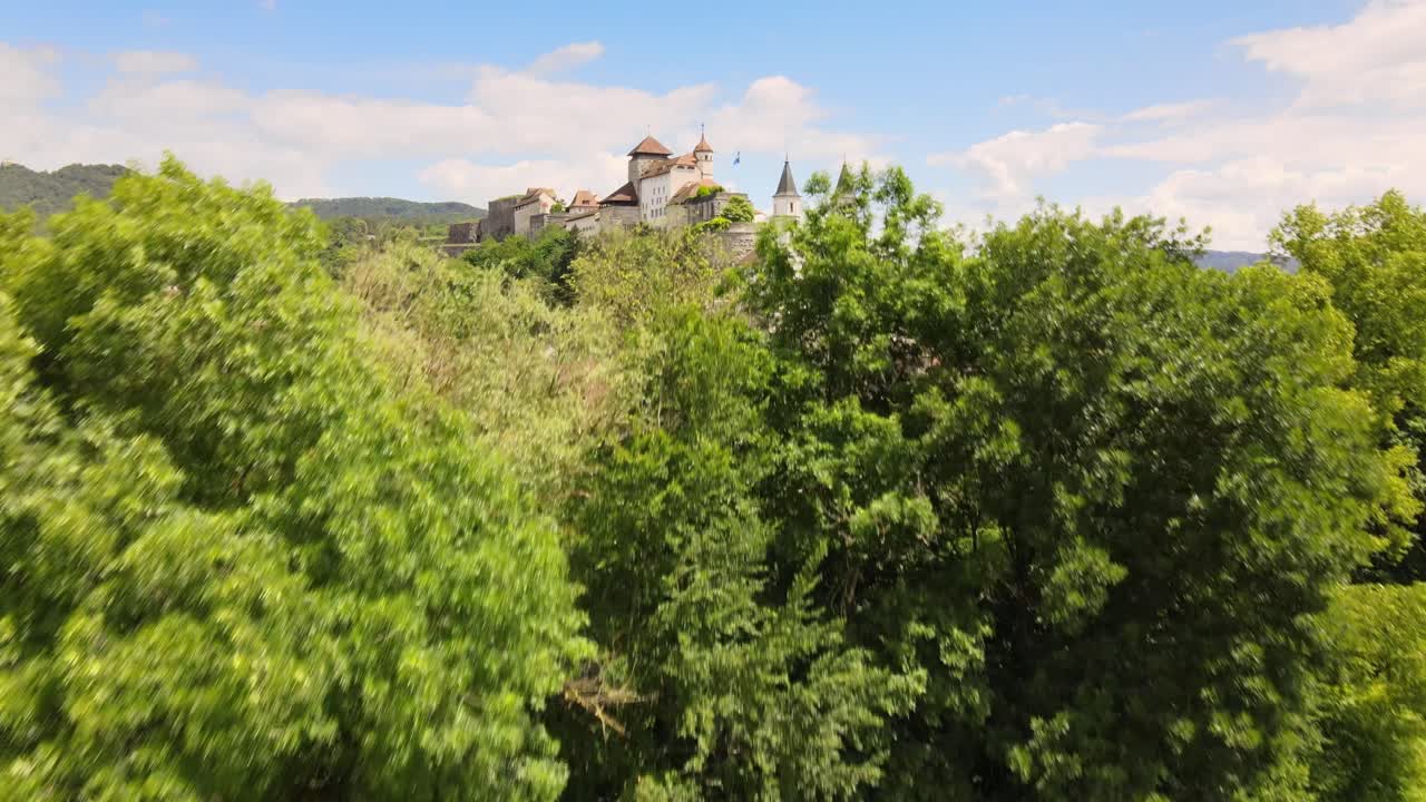 кинематографическая съемка с беспилотного летательного аппарата, показывающая церковь и крепость на холме за деревьями в городе аарбург в швейцарии