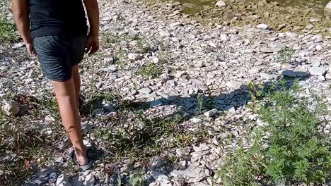 persona caminando a lo largo de una orilla rocosa