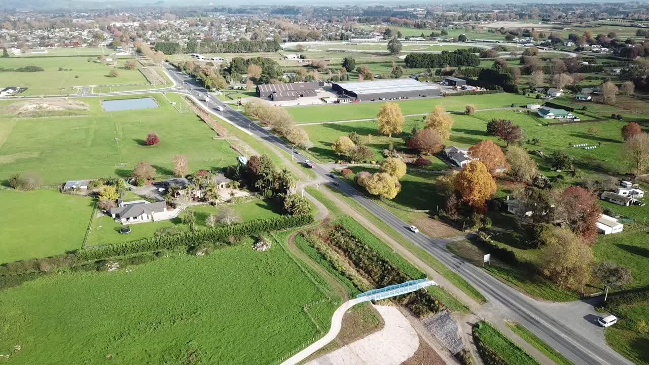 disparo desplegable de drones, volando hacia la autopista con automóviles, césped y árboles en la zona residencial de cambridge, nueva zelanda.
