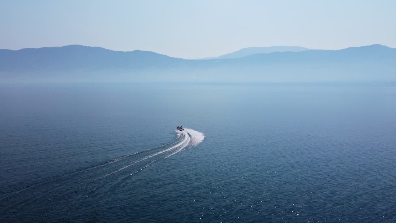 캐나다 산불 시즌 동안 더운 날 깊고 푸른 오카나간 호수 위로 커브를 빠르게 달리는 쾌속정