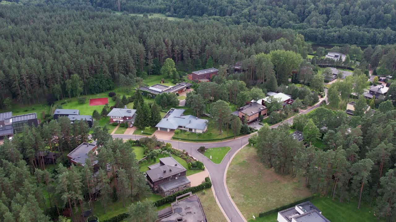 Aerial view of a forest-edge suburban district with modern homes, winding roads, and dense pine woods, showcasing tranquil residential living blended seamlessly with natural greenery