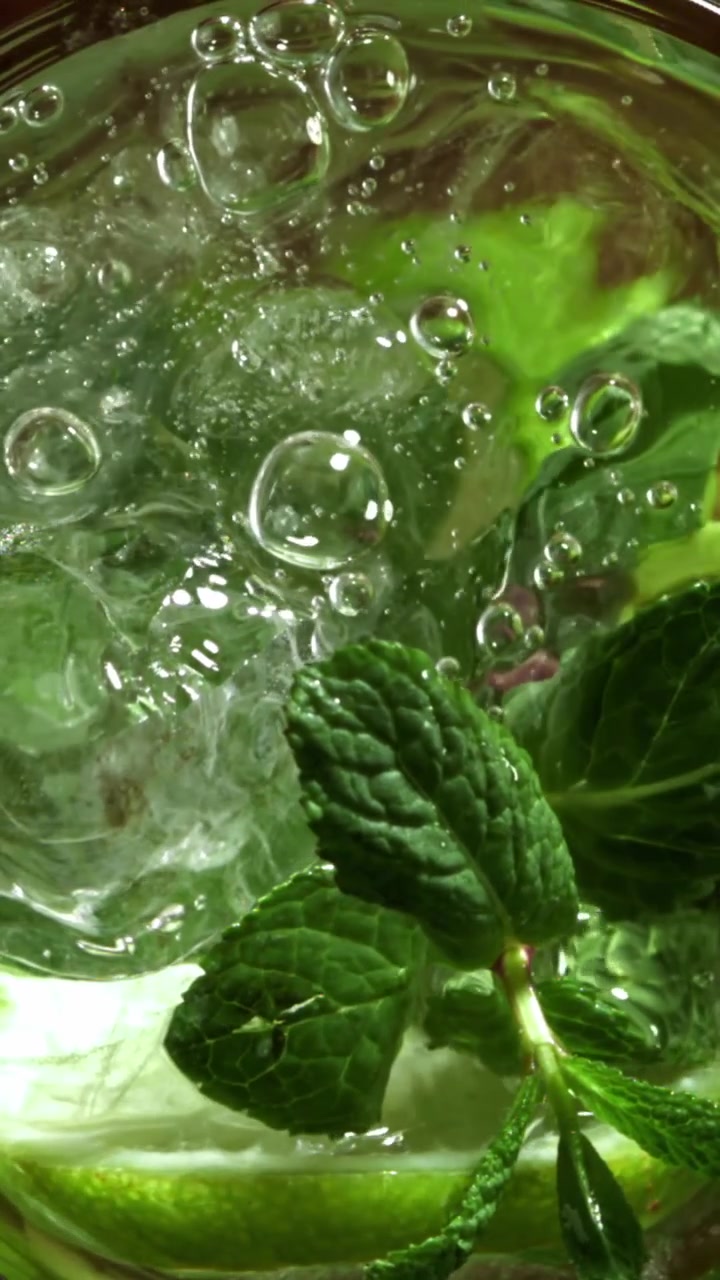 Versare acqua su ghiaccio, menta e lime per una bevanda rinfrescante