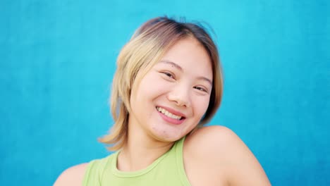 chinese woman smiling at camera next to a blue wall