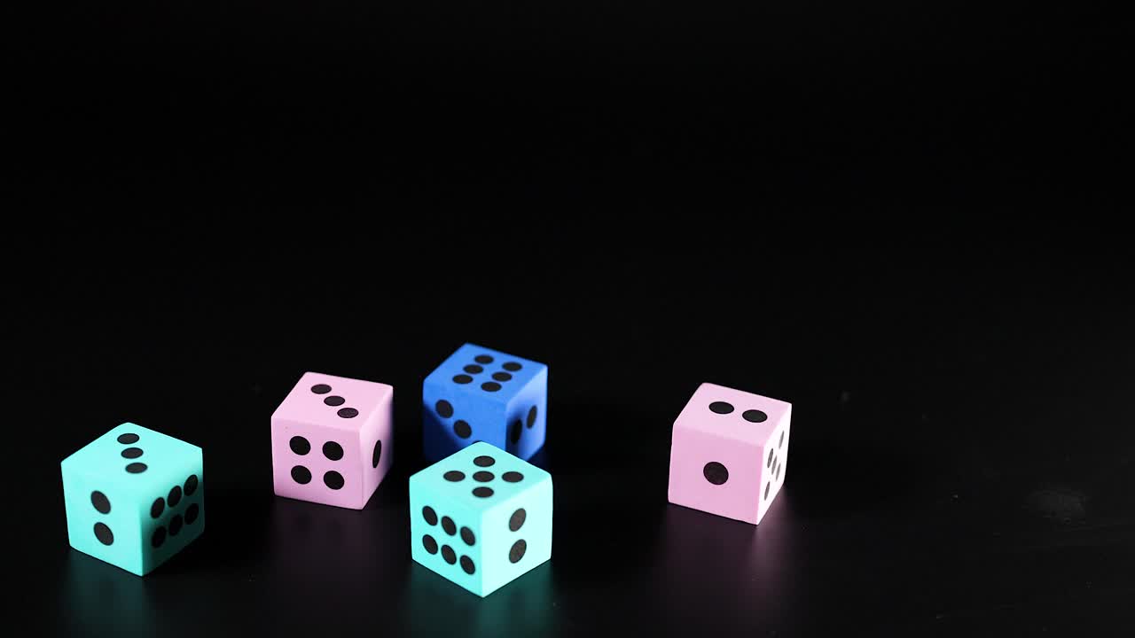 varios dados de colores rodando y asentándose en la superficie negra