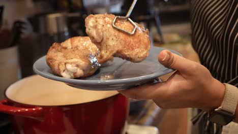 taking steaming hot chicken out of the cast-iron pot where they have been roasting - pot roasted chicken series