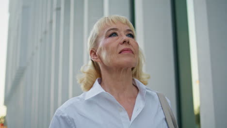 wrinkled lady walking city street close up. aged woman strolling urban district