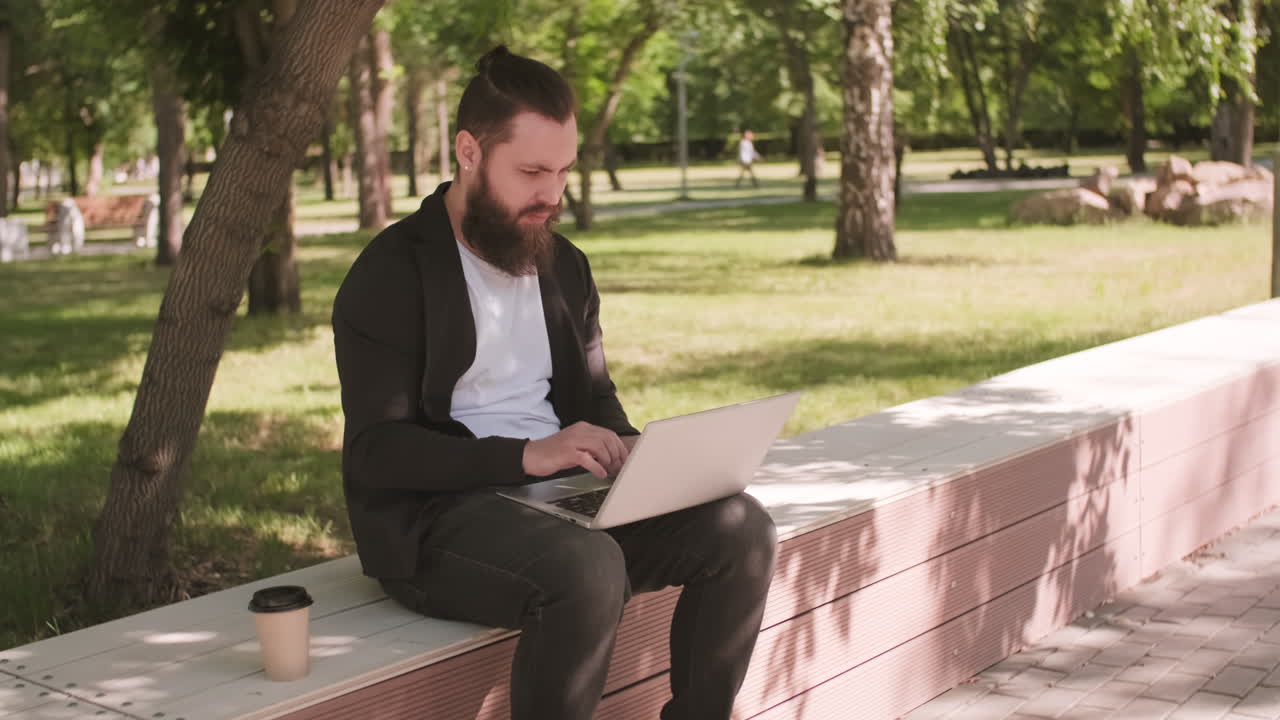 Bearded Young Man Working on Laptop in Park
