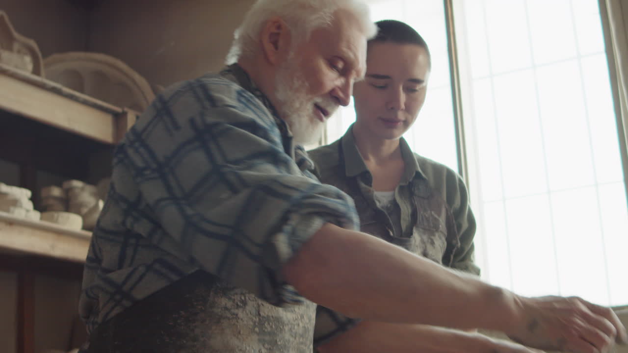 Senior Artisan Teaching Young Woman Pottery