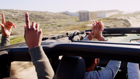 amigos masculinos en el coche con techo solar pegando las manos en el aire