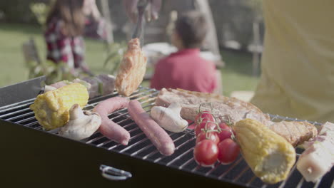 Close-up-of-man-standing-at-barbeque-grill-and-turning-over-meat